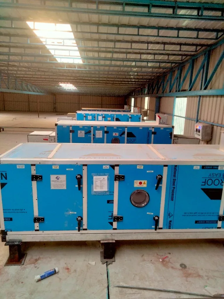 Blue air-handling units inside a large metal-roofed facility