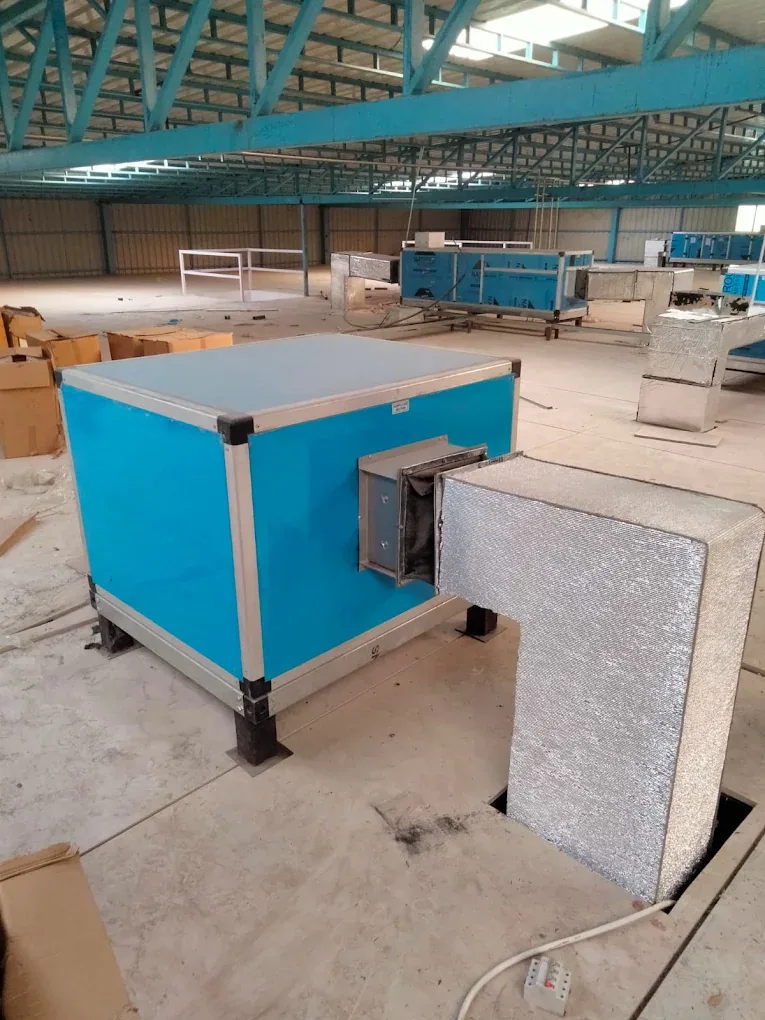 Blue air-handling unit connected to insulated ductwork inside a large facility