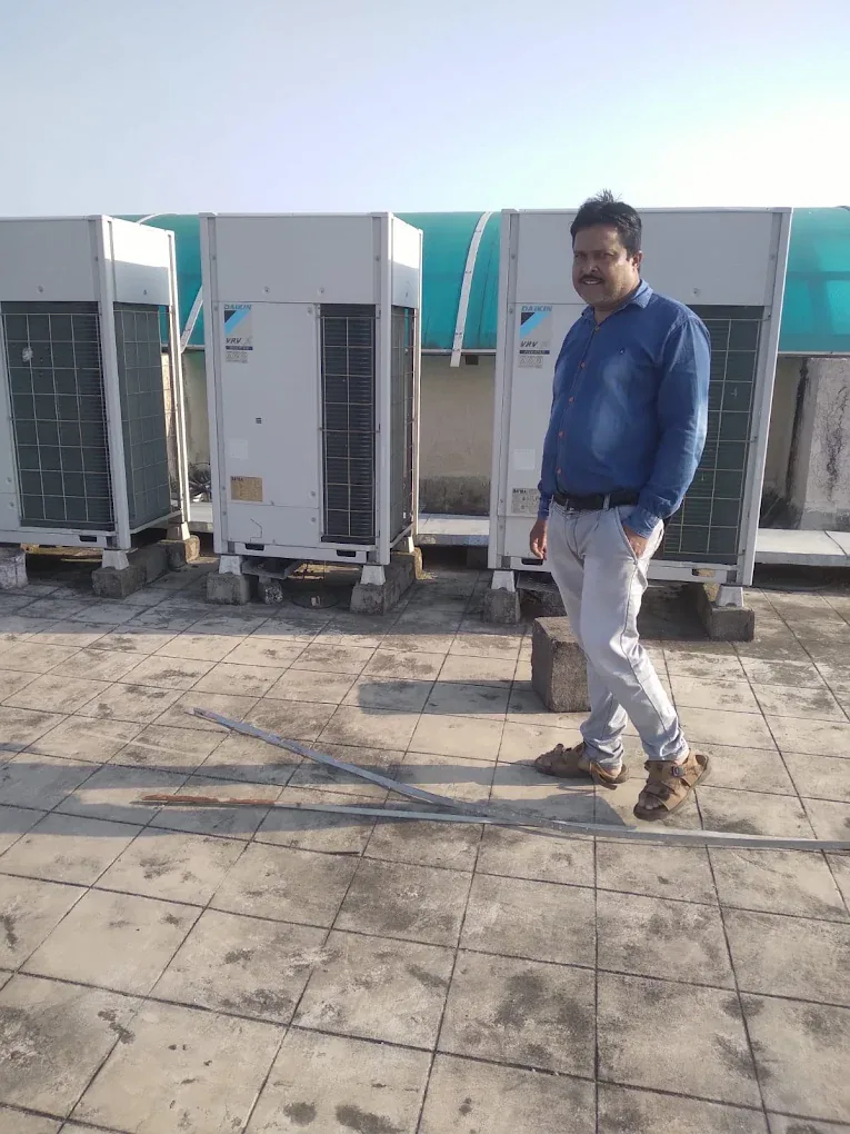 Man standing beside three Daikin VRV outdoor units on a rooftop