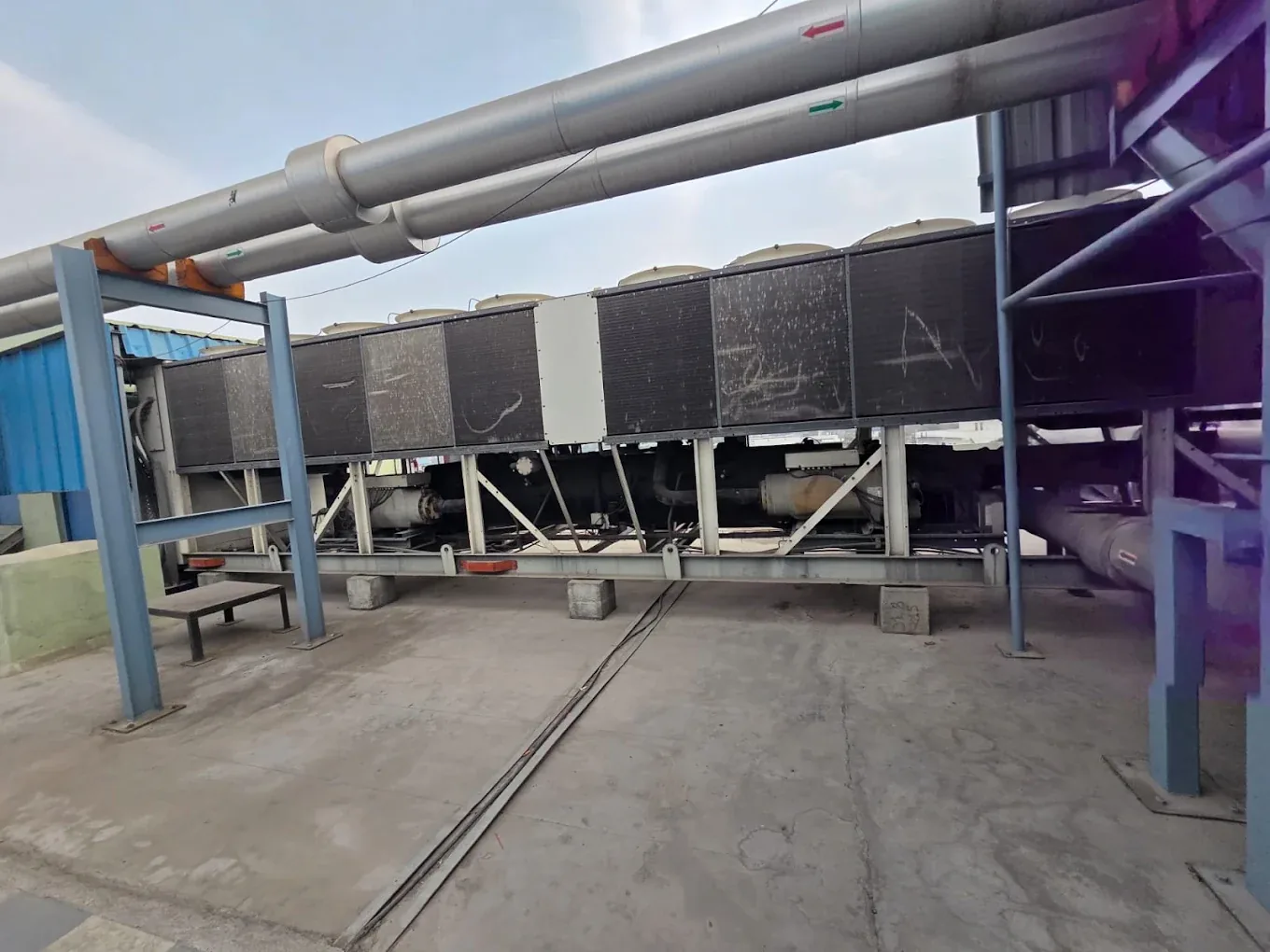 Large rooftop chiller unit beneath insulated pipework