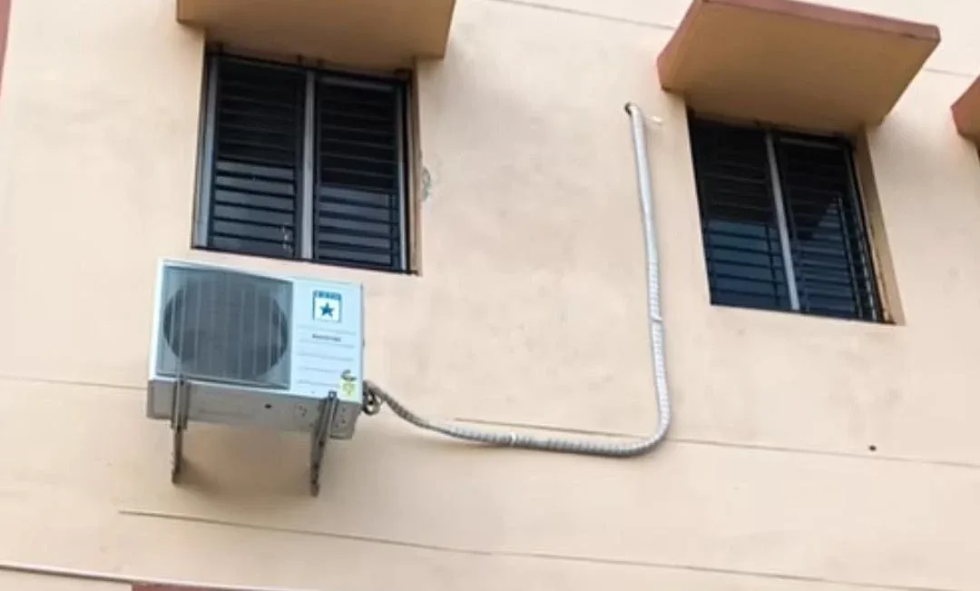 Split AC outdoor unit mounted on an exterior wall with insulated piping